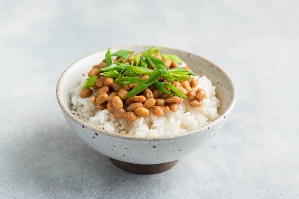 Bowl of white rice topped with natto and chopped green onions (scallions).