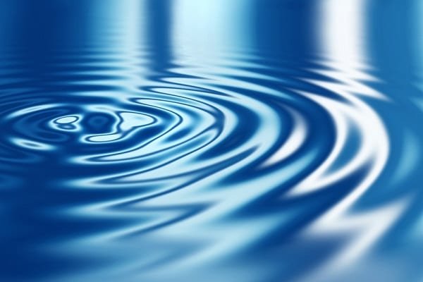 Blue water surface with gentle ripples spreading outward across the blue surface. If used as an abstract image, conveys calm water motion.