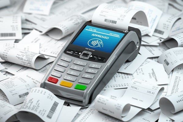 Payment terminal with an 'Approved' screen, surrounded by scattered receipts.