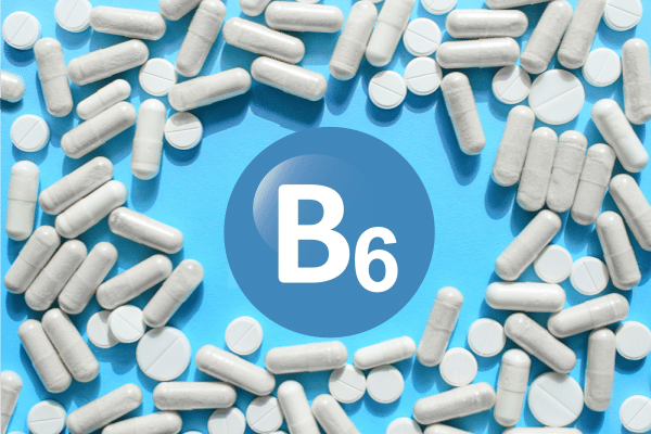 Blue background with a central blue circle labeled 'B6' surrounded by white pills and tablets, indicating vitamin B6 supplements.