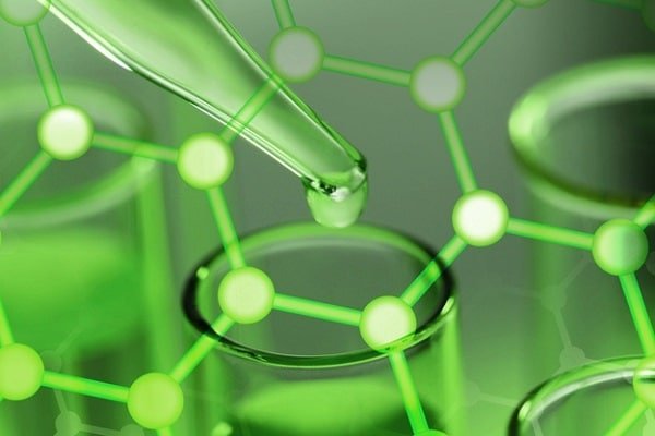 Pipette releasing liquid into a test tube with a green molecular structure overlay, highlighting chemistry research.