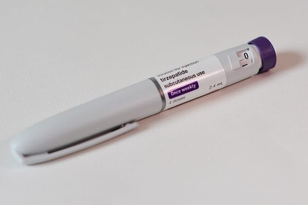 Disposable subcutaneous injection pen with purple cap labeled for once‑weekly use (tirzepatide).