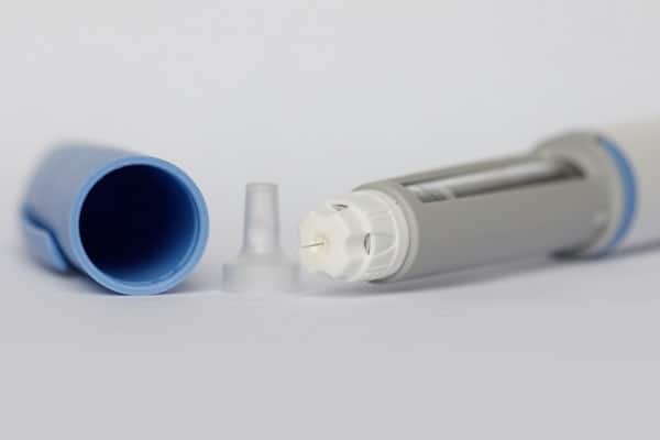 Close-up of an inhaler with the mouthpiece exposed and the blue cap removed on a white surface.